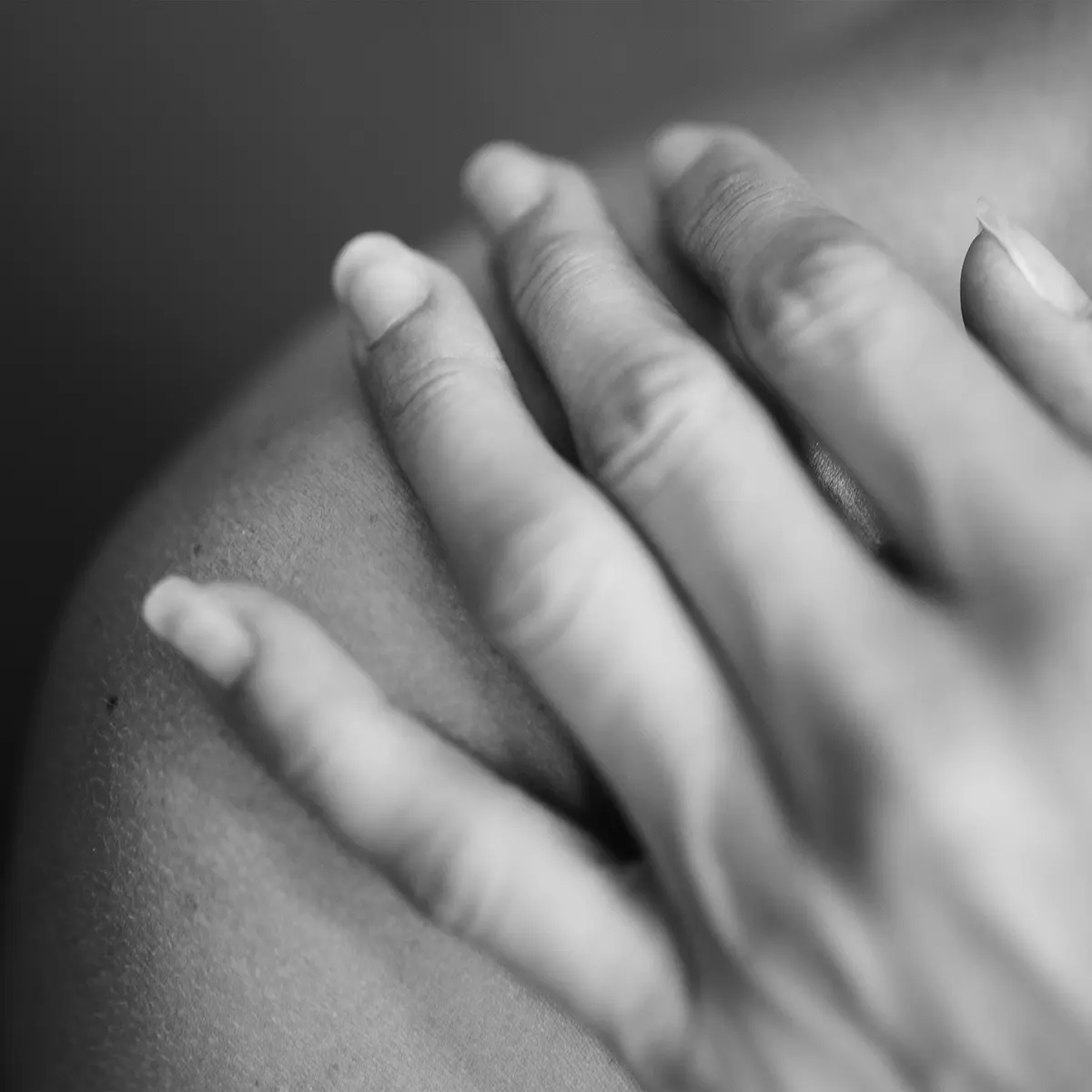 Detalle en blanco y negro de una mano apoyada en el hombro